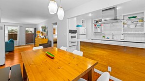 Eine moderne Küche mit weißen Schränken, einem Holztisch und Pendelleuchten.