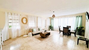 A spacious living room with a sofa, coffee table, and dining area. - Serene Barbados escape with ocean view - Peaceful (Christ Church)