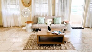 A living room with a beige sofa, two side tables, a coffee table, and a patterned rug. - Serene Barbados escape with ocean view - Peaceful (Christ Church)