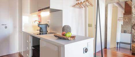 A modern kitchen with white cabinetry, a built-in oven, and a fruit bowl on the counter.