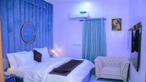 Un dormitorio con cama, sofá, televisión y aire acondicionado.