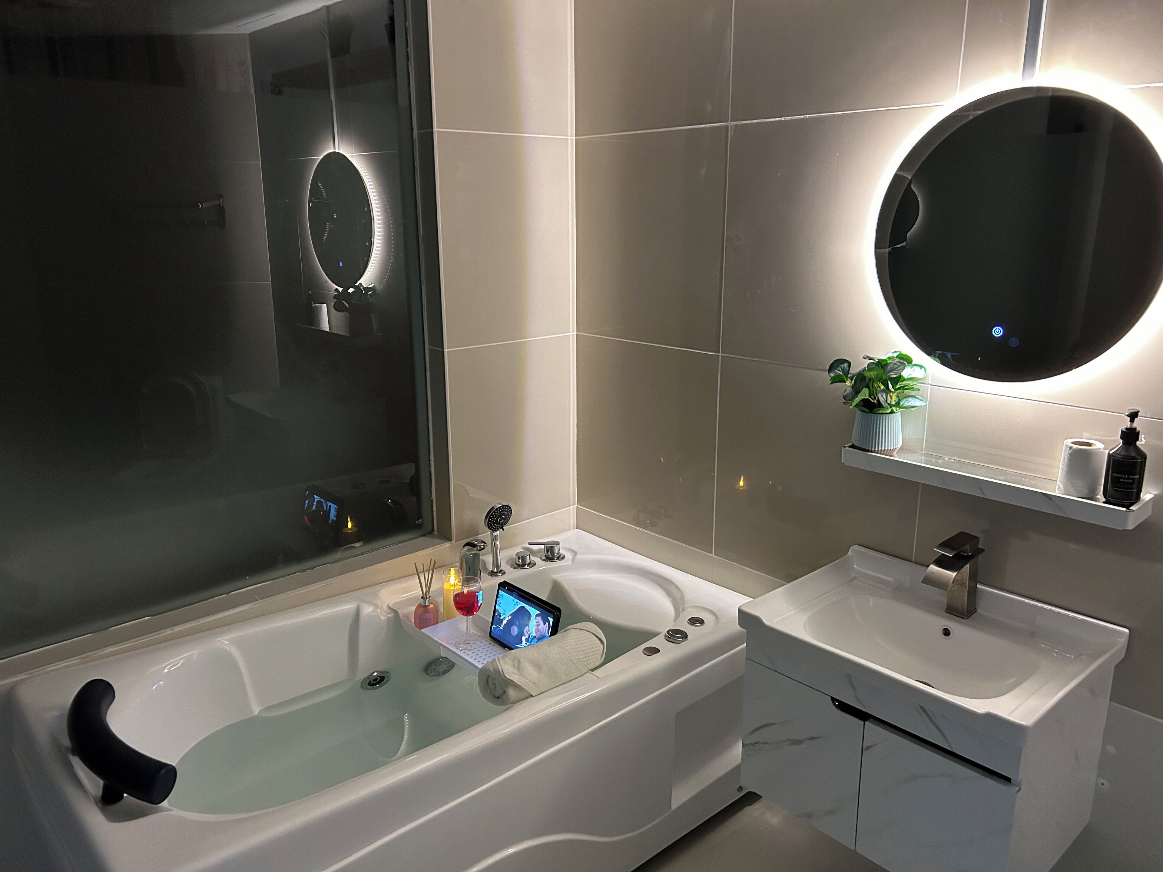 Een moderne badkamer met een groot bad, een aparte wastafel en een spiegel boven de wastafel.