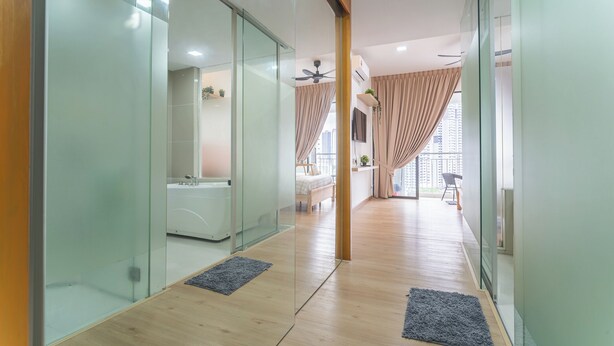 A modern hotel corridor with glass walls, a wooden floor, and a view of a bedroom with a bed and curtains. - [NEW] Private Jacuzzi | Near Velocity Mall | MRT | Retro Games (Cheras)