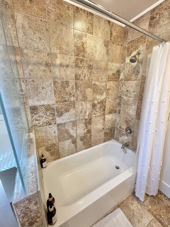 A bathroom with a bathtub, shower, and glass shower enclosure.