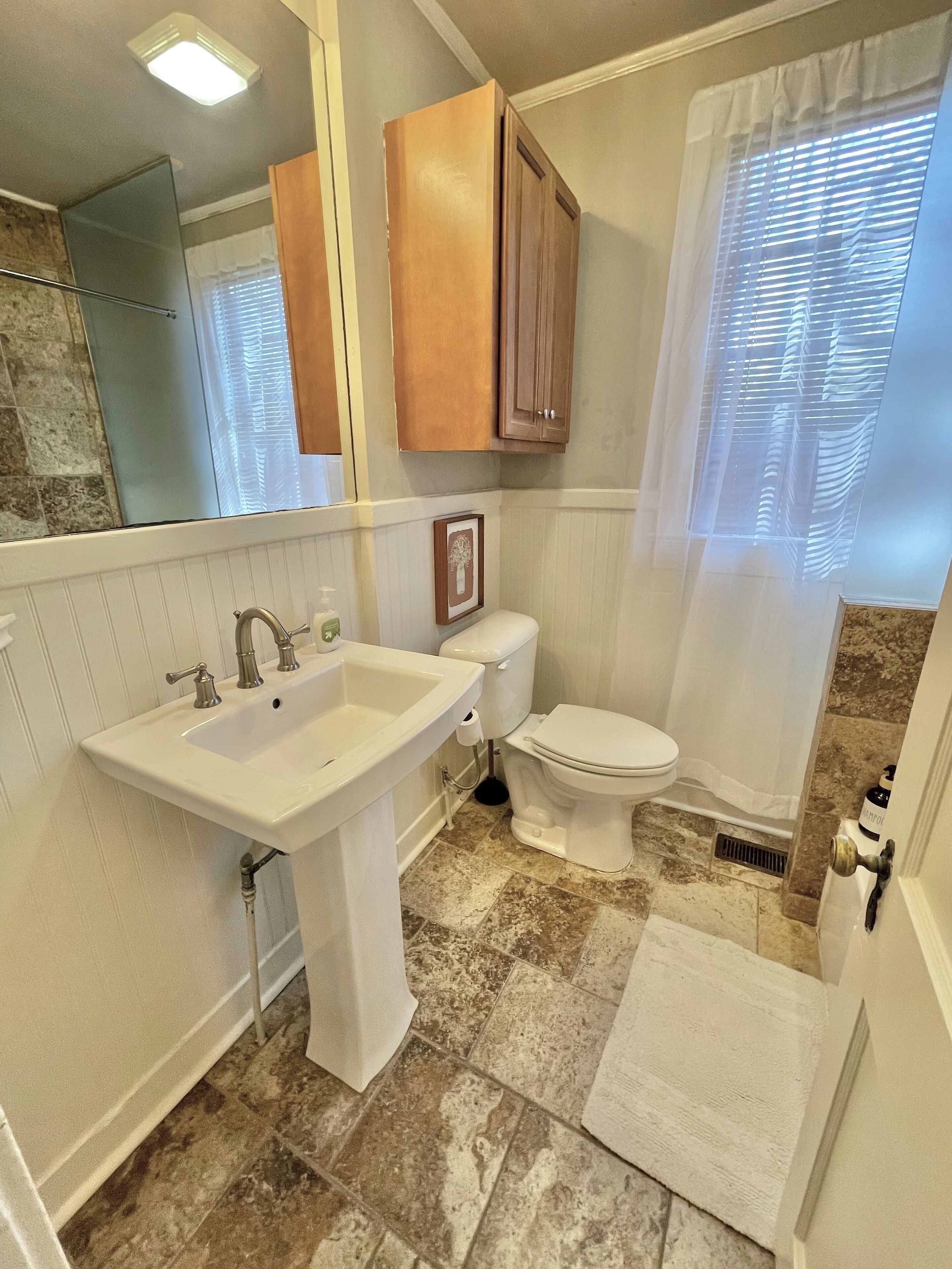 A bathroom with a white sink, toilet, and shower curtain.