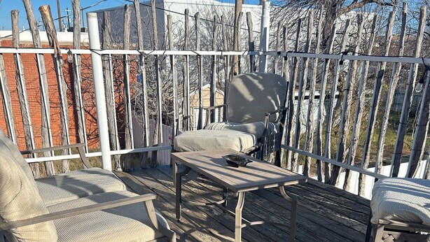 Eine Holzterrasse mit Metallstühlen und einem Tisch.