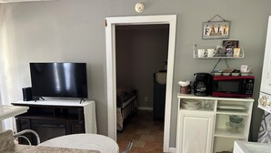 A compact living space with a TV on a stand, a dining table, a kitchen area with a microwave, coffee maker, and a small refrigerator. - Little Southern Charm in tranquil Flovilla with AC, WiFi (Flovilla)