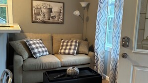 A living room with a sofa, a black coffee table with a decorative item, a framed picture on the wall, and a lamp. - Little Southern Charm in tranquil Flovilla with AC, WiFi (Flovilla)
