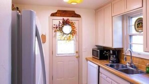 A kitchen with a refrigerator, microwave, coffee maker, and sink. - Tinker AFB OKC I-40 Colonial Dorchester Cottage (Midwest City)