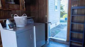 A laundry area with a washing machine, a dryer, and a white laundry basket on a counter.