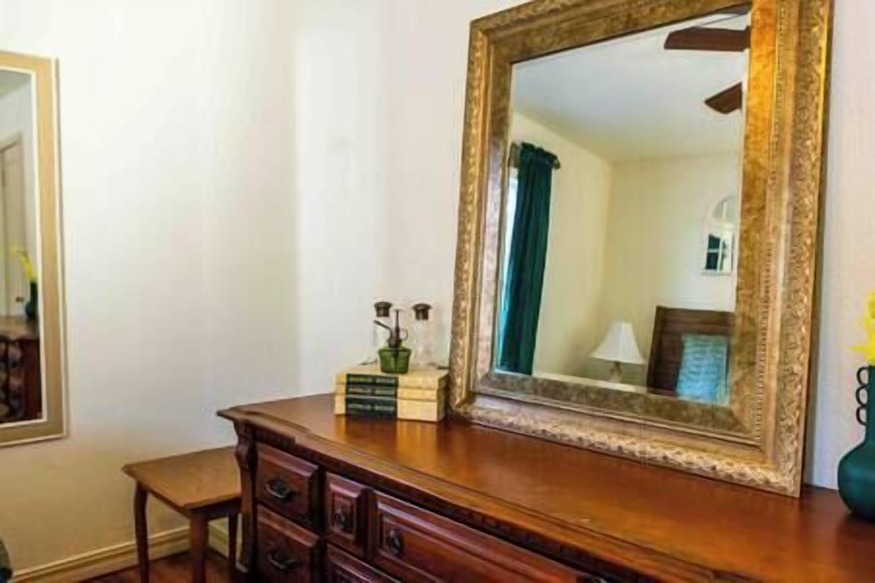 Une commode en bois avec un miroir et une petite table placée à côté.