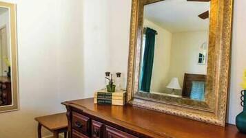 Une commode en bois avec un miroir et une petite table placée à côté.