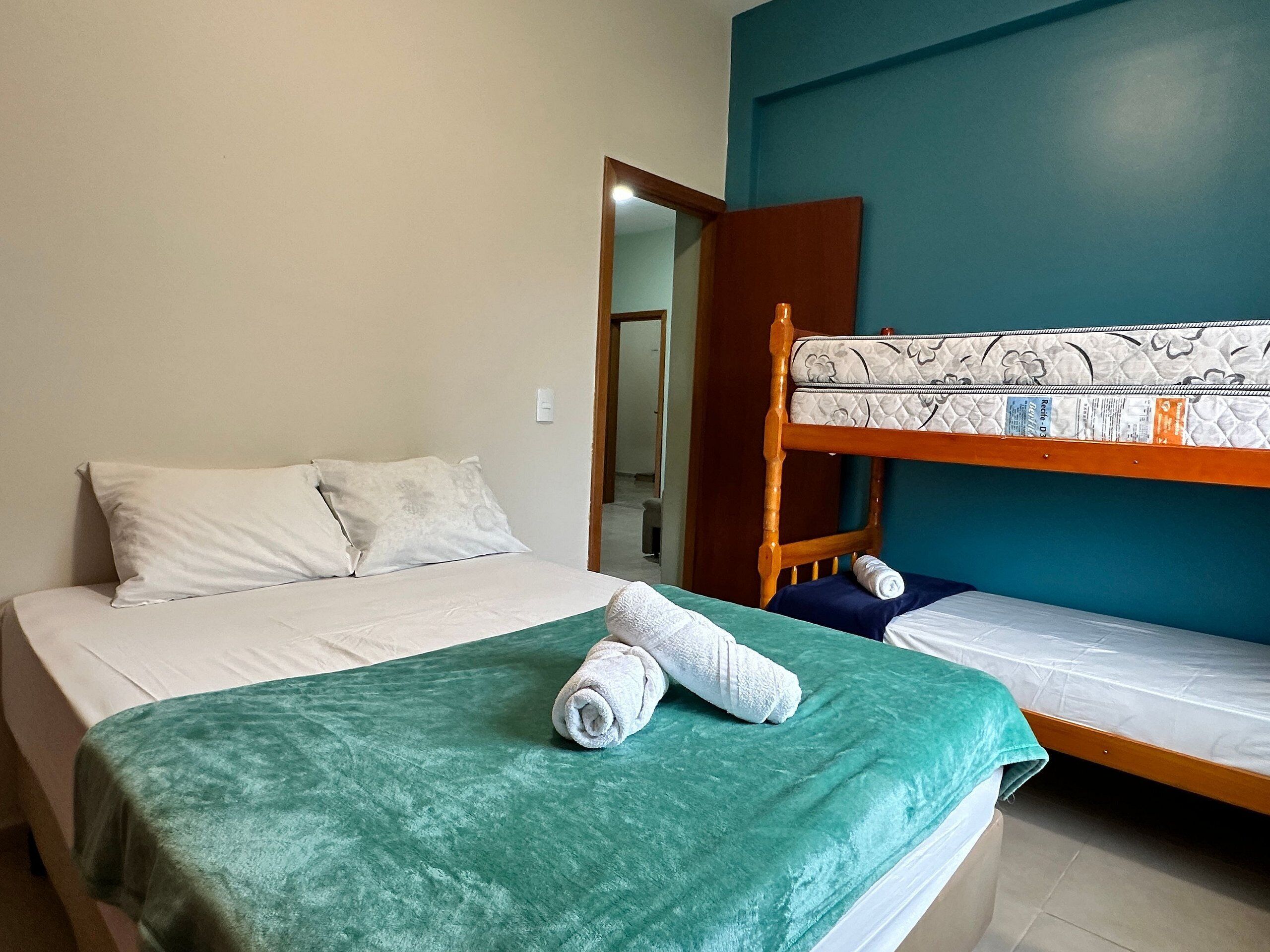 A room with a bunk bed, a single bed, and a green bedspread.