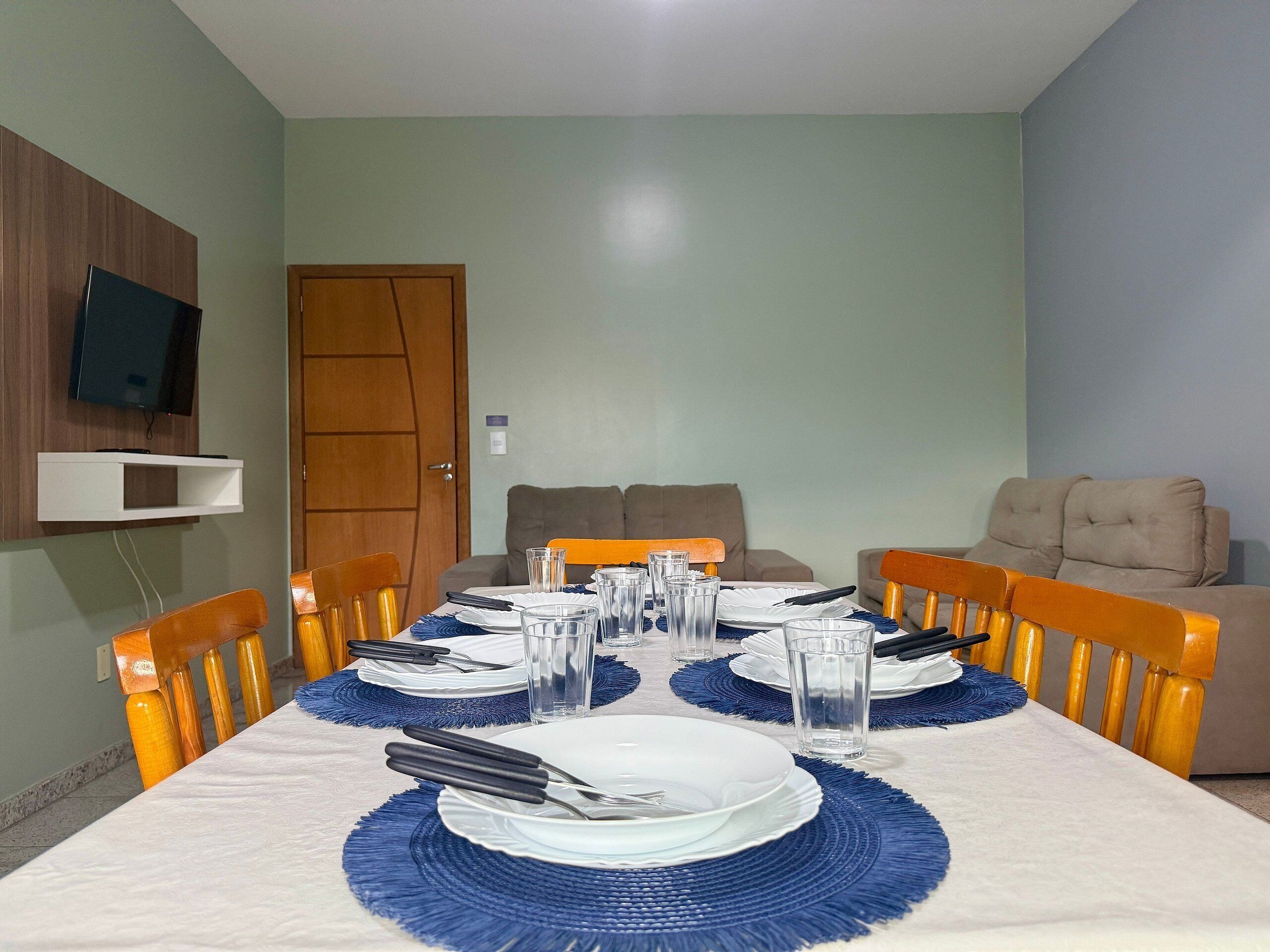 A dining area with a long table set for four, surrounded by wooden chairs.