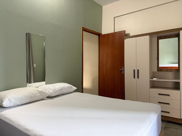 Une chambre à coucher avec un lit, une armoire et un miroir.