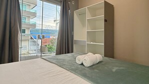 Een hotelkamer met een bed, een kledingkast en een raam met gordijnen.