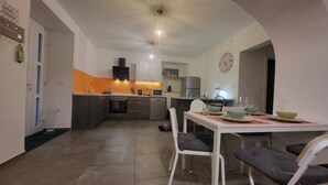A compact kitchen with modern appliances, a dining area with a table set for two, and a clock on the wall. - Appartamento Soul & Travel Ac And Wifi (Opatija)