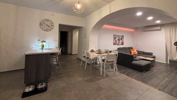 A modern living room with a dining area, featuring a kitchen island, a sofa, and a dining table with chairs. - Appartamento Soul & Travel Ac And Wifi (Opatija)