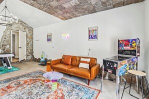 Una sala de estar con un sofá, una mesa de centro, un tapete, una pared de piedra y una puerta.