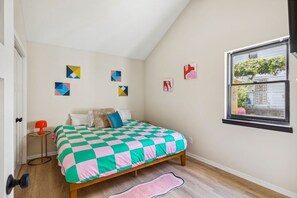 Un dormitorio con edredón de cuadros, una ventana con vistas y decoración en la pared.
