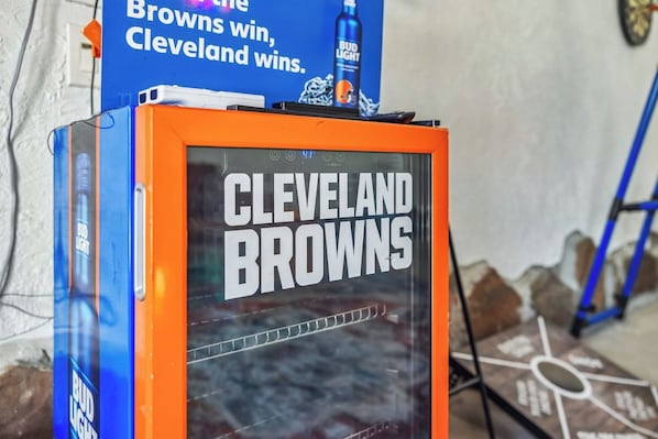A framed sign with 'Cleveland Browns' text, a Bud Light advertisement, and a dartboard in the background.