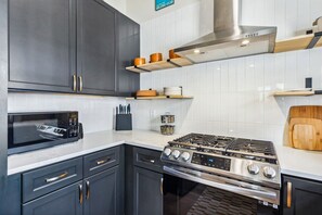 A modern kitchen with dark cabinets, a stainless steel stove, and a microwave.
