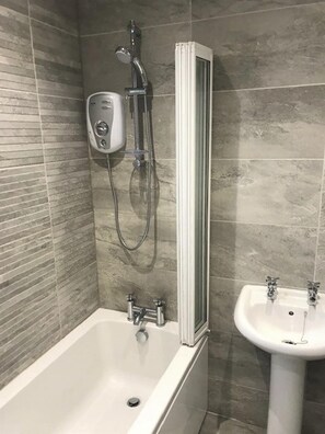 A bathroom with a bathtub, a shower, and a sink.