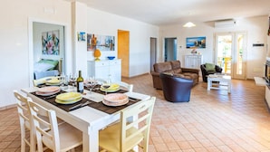 A spacious living area with a dining table set for a meal, a sofa, and a coffee table.