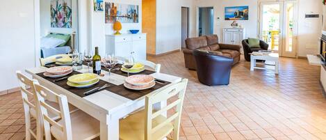 A spacious living area with a dining table set for a meal, a sofa, and a coffee table.