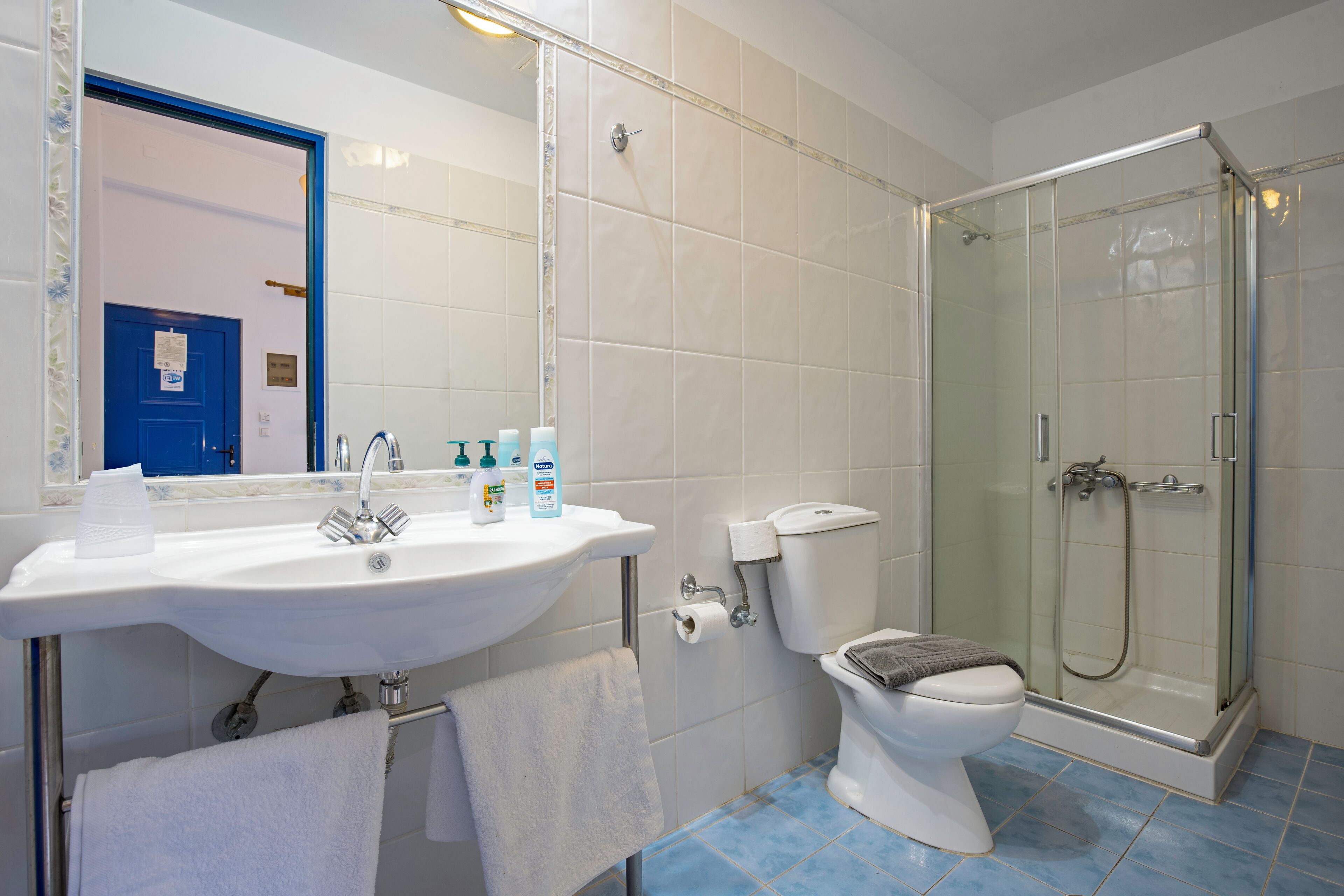 Un baño con lavamanos blanco, inodoro y ducha con mampara de vidrio.