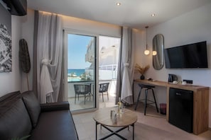 Una habitación moderna con sofá, una mesa de comedor con sillas, una zona de cocina y un televisor.