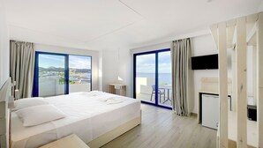 A modern hotel room with a large bed, a desk, a flat-screen TV, and a balcony with a view of the sea. - RAFFAELLO BEACH (Rhodes)
