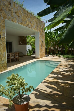 A pool area with stone walls, a patio with chairs, and a potted plant. - Luxury Villa JULITO, in Private Complex, near Sandbank Beach. (Kiwengwa)