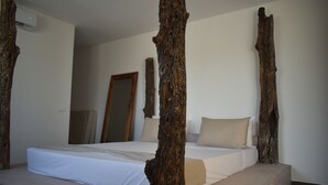 Ein Schlafzimmer mit einem großen Bett, Holzbalken, einem Spiegel und einer Tür.