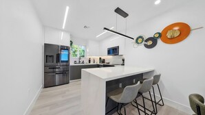 A modern kitchen with a central island, stainless steel appliances, and a minimalist design. - New Design Dist Gem:Pool,HotTub,Minigolf,Nespresso (Miami)