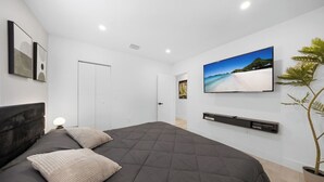 A modern bedroom with a large bed, a flat-screen TV, a potted plant, and a minimalist design. - New Design Dist Gem:Pool,HotTub,Minigolf,Nespresso (Miami)