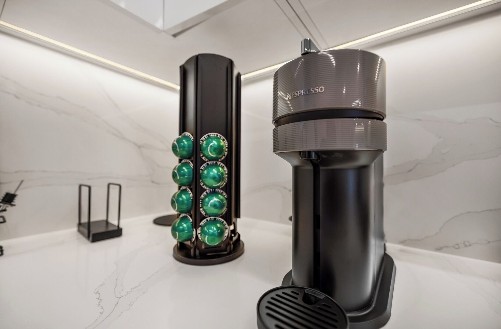 Una cocina moderna con una máquina de espresso negra y un molinillo de café verde.