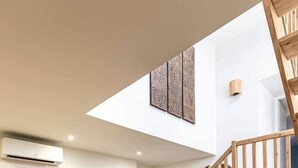 A modern living room with a grey sofa, a small coffee table, and a staircase leading to an upper level. - Cozy duplex - patio - sleeps 6 - historic village (Saint-Paul-Trois-Châteaux)