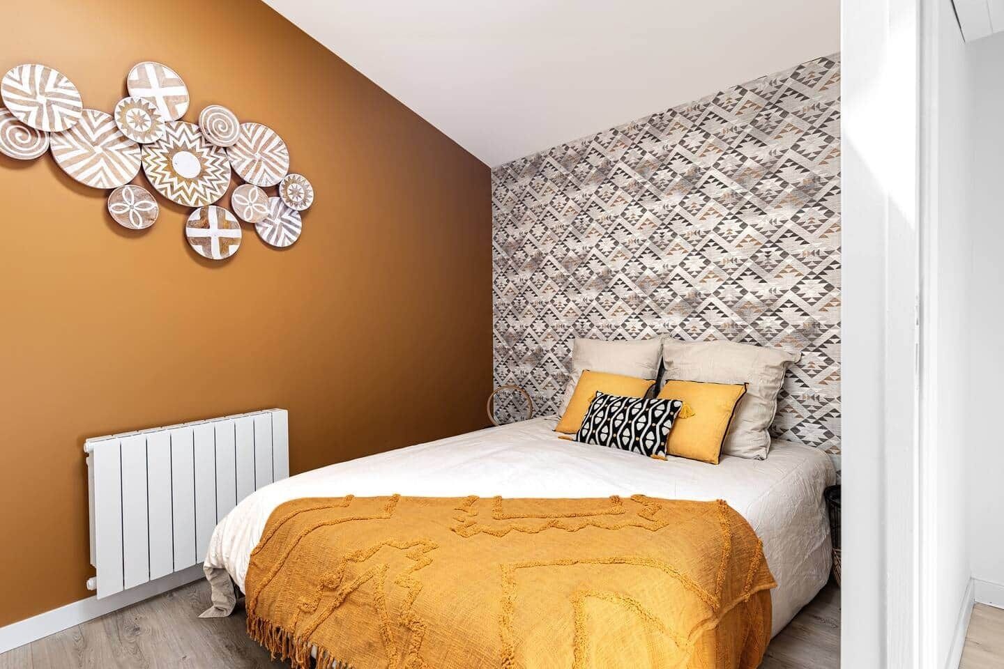 Quarto com cama, radiador e parede estampada.