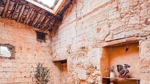 A rustic stone-walled courtyard with a wooden bench, two cushioned chairs, and a small table. - Cozy duplex - patio - sleeps 6 - historic village (Saint-Paul-Trois-Châteaux)