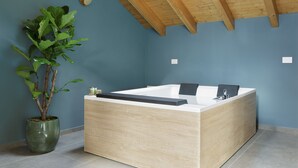 Un baño moderno con una bañera de madera, una planta en maceta y una pared azul.