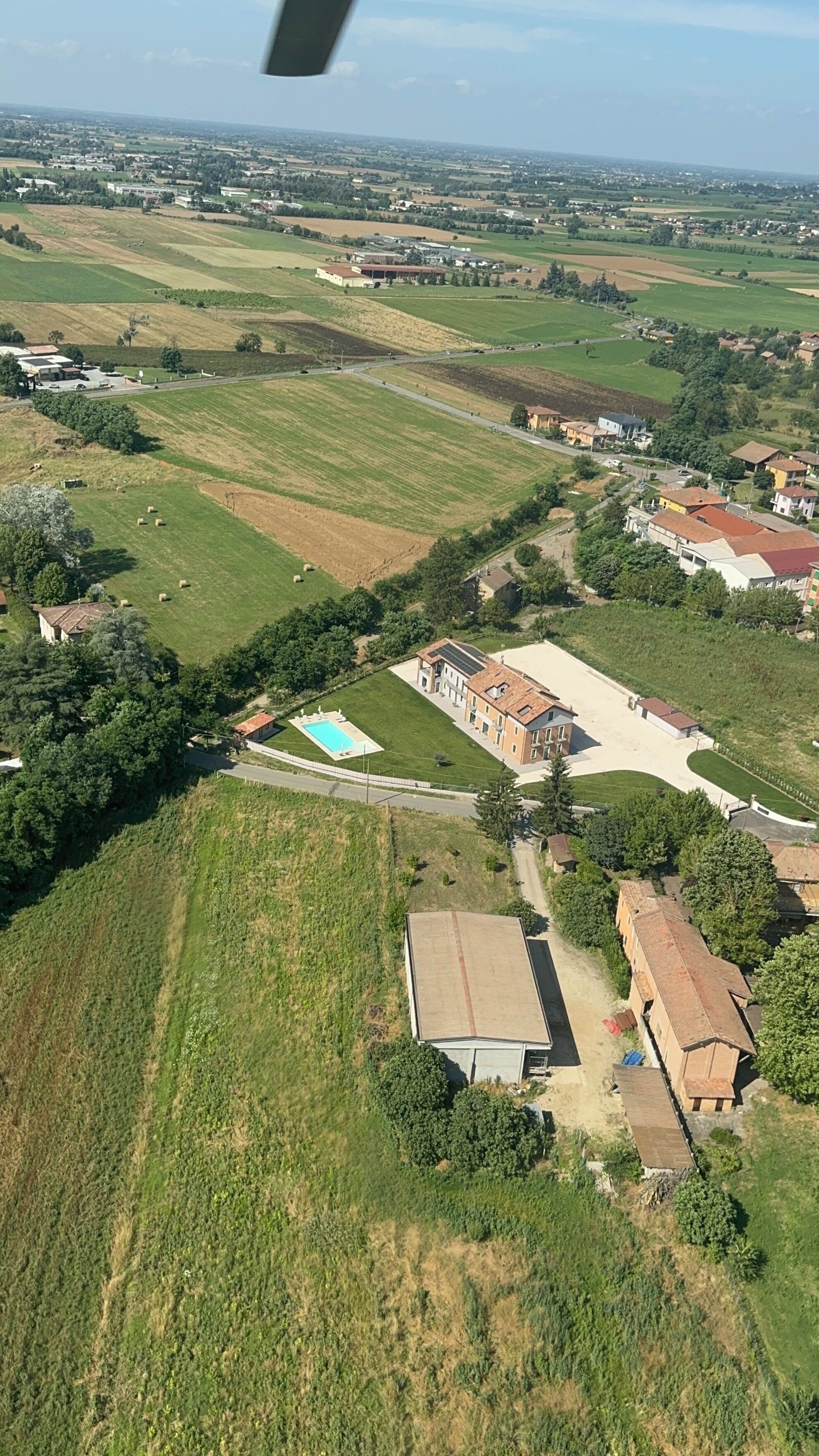 Vista aérea de uma zona rural com campos, uma piscina e vários edifícios.