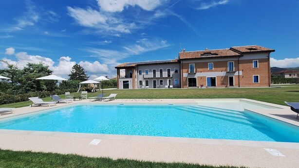 A swimming pool with lounge chairs, a building with multiple windows, and a clear blue sky.
