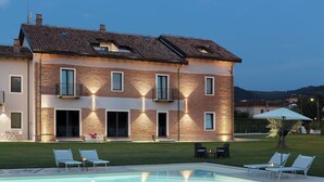 Una casa moderna con piscina, dos sillones de descanso y una pequeña mesa.