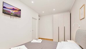 Une chambre à coucher avec un lit, un téléviseur fixé au mur et une armoire.
