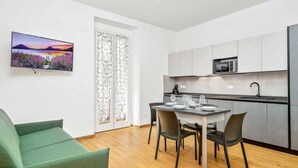 Un appartement moderne comprenant un coin repas, une cuisine et un téléviseur diffusant des images de paysages.