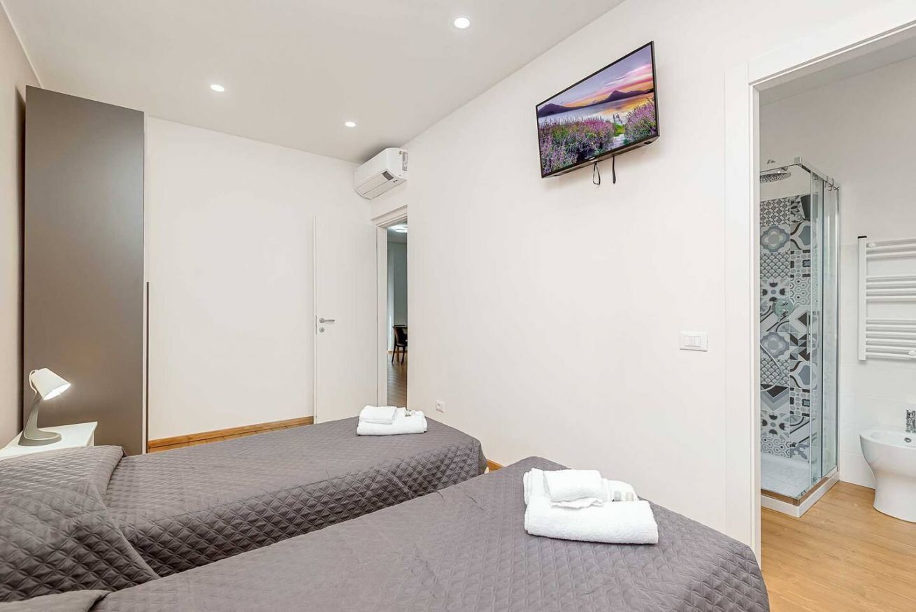 Ein Hotelzimmer mit zwei Betten, einem Fernseher, einer Dusche und einem Badezimmer.