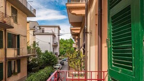 Une rue étroite, bordée de bâtiments des deux côtés, avec des balcons et une porte verte.