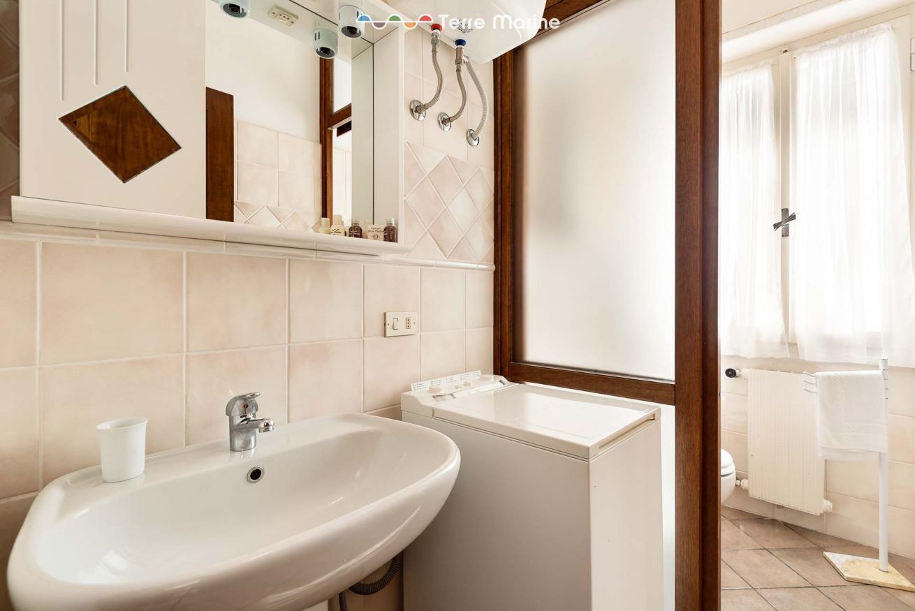 A bathroom with a sink, mirror, and a window with curtains.