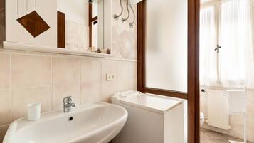 A bathroom with a sink, mirror, and a window with curtains.